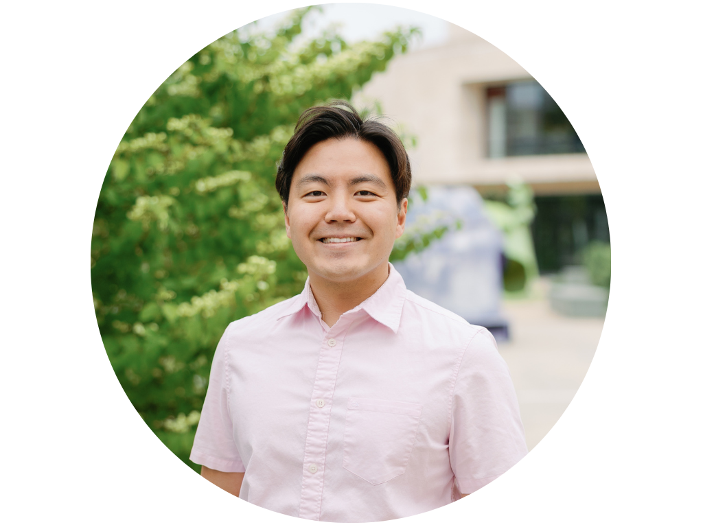 Man smiling in a park with trees in the background.