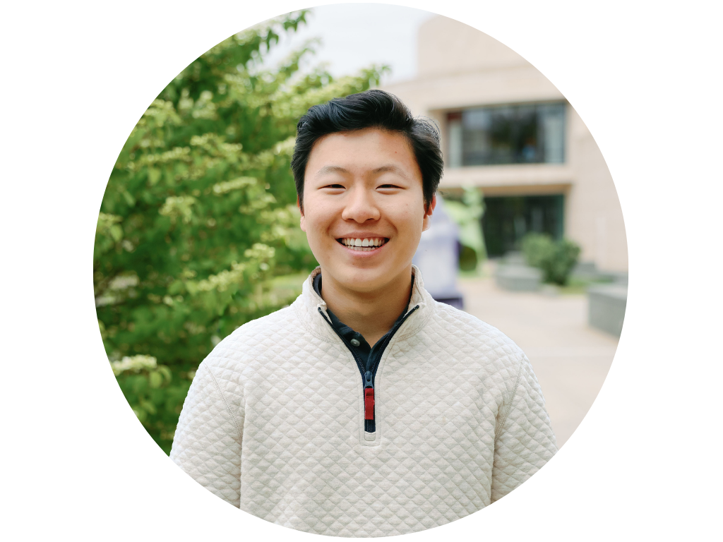 Person smiling outdoors with trees in background