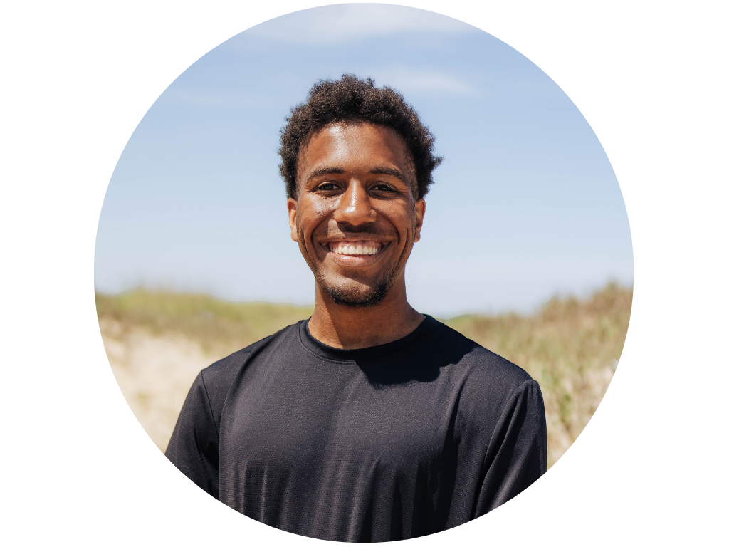 Smiling person in a black shirt with a background of green hills.