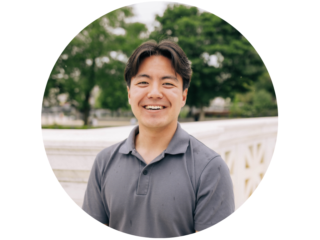 Man smiling in a park with trees in the background.