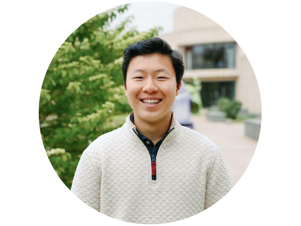 Person smiling outdoors with trees in background
