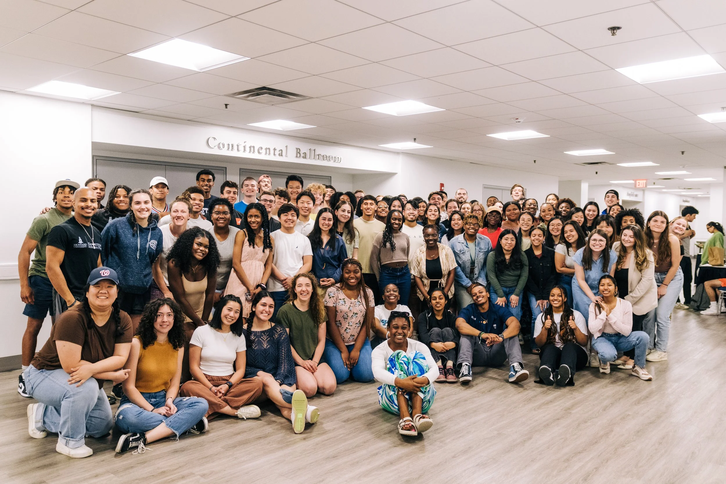 Large group of people smiling indoors.