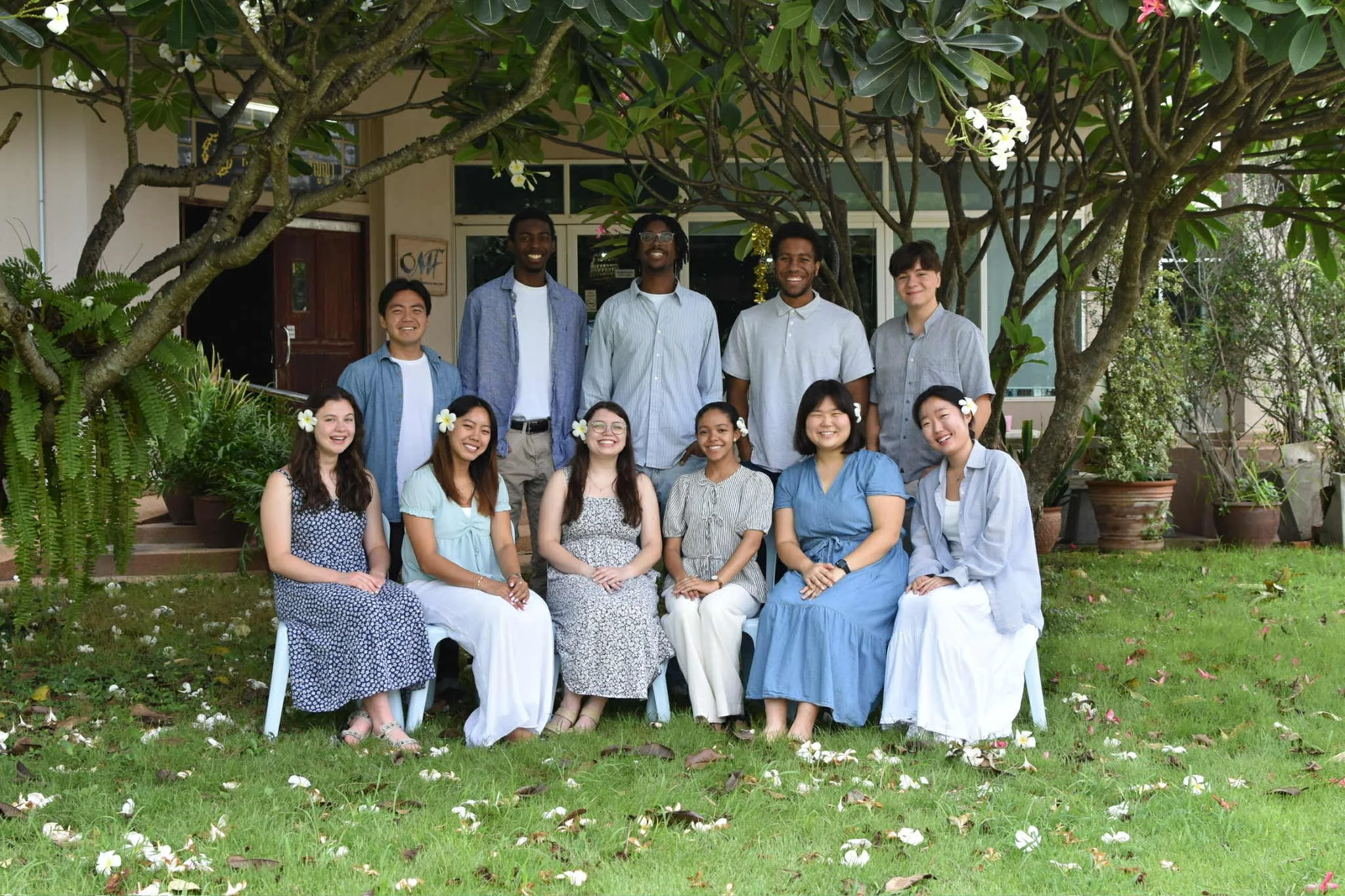 A large group of diverse people posing outdoors on a snowy landscape with hills in the background.