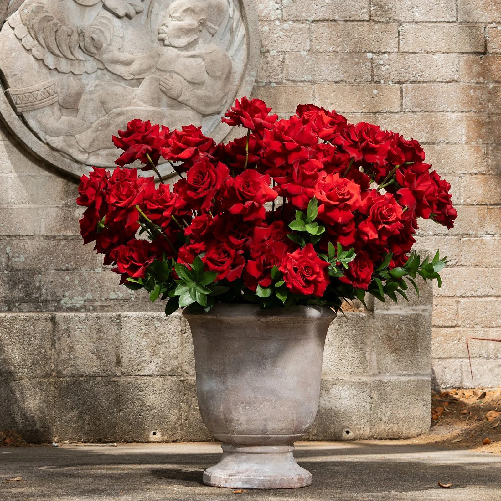 100 reflexed roses arranged in a full, sculptural and romantic floral composition with open blooms