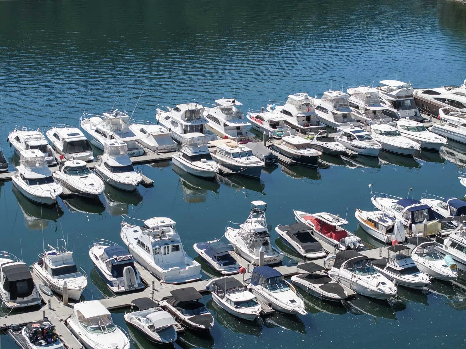 Aerial view of a marina with numerous boats docked on calm blue water.