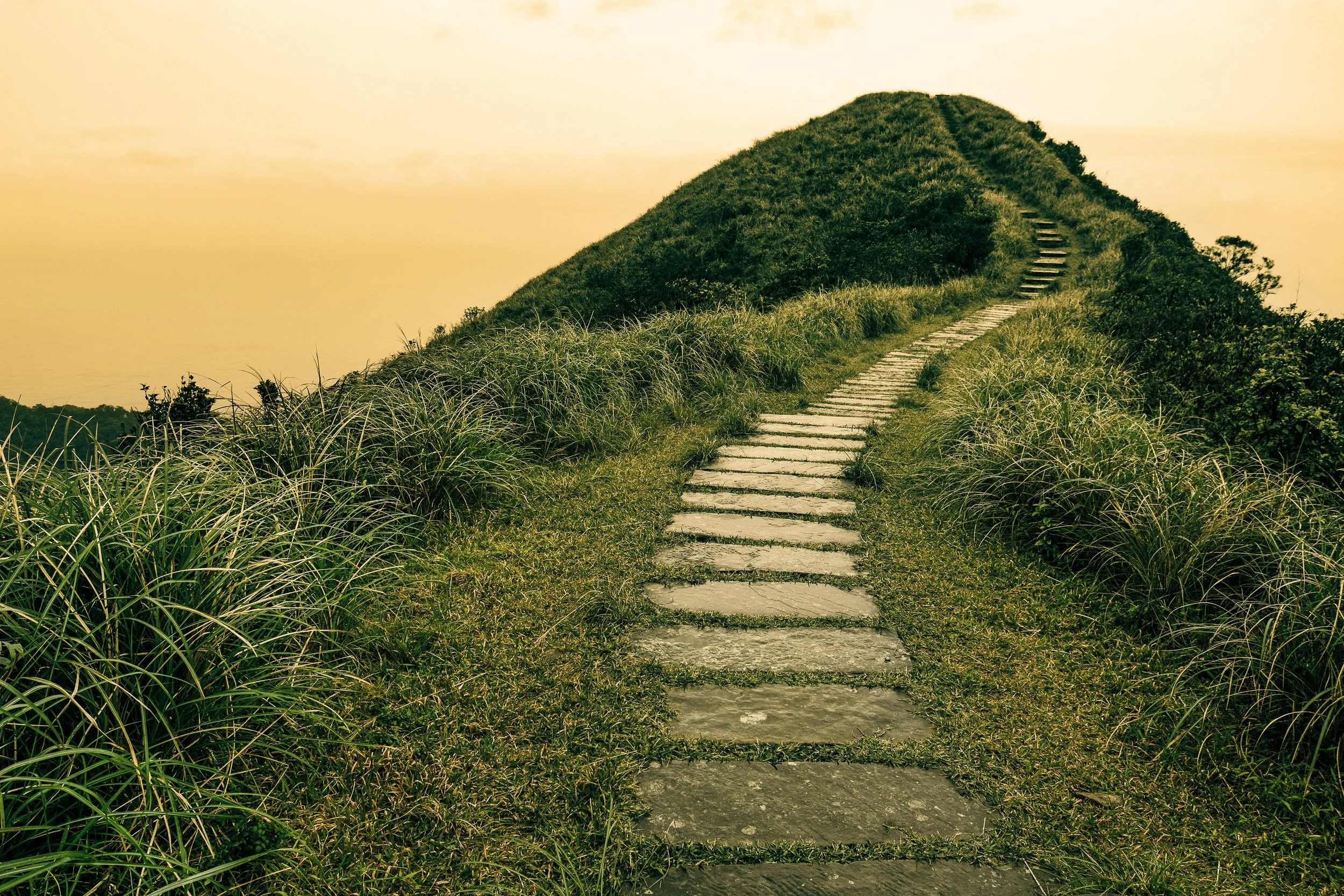 A paved pathway leading along the crest of a hill