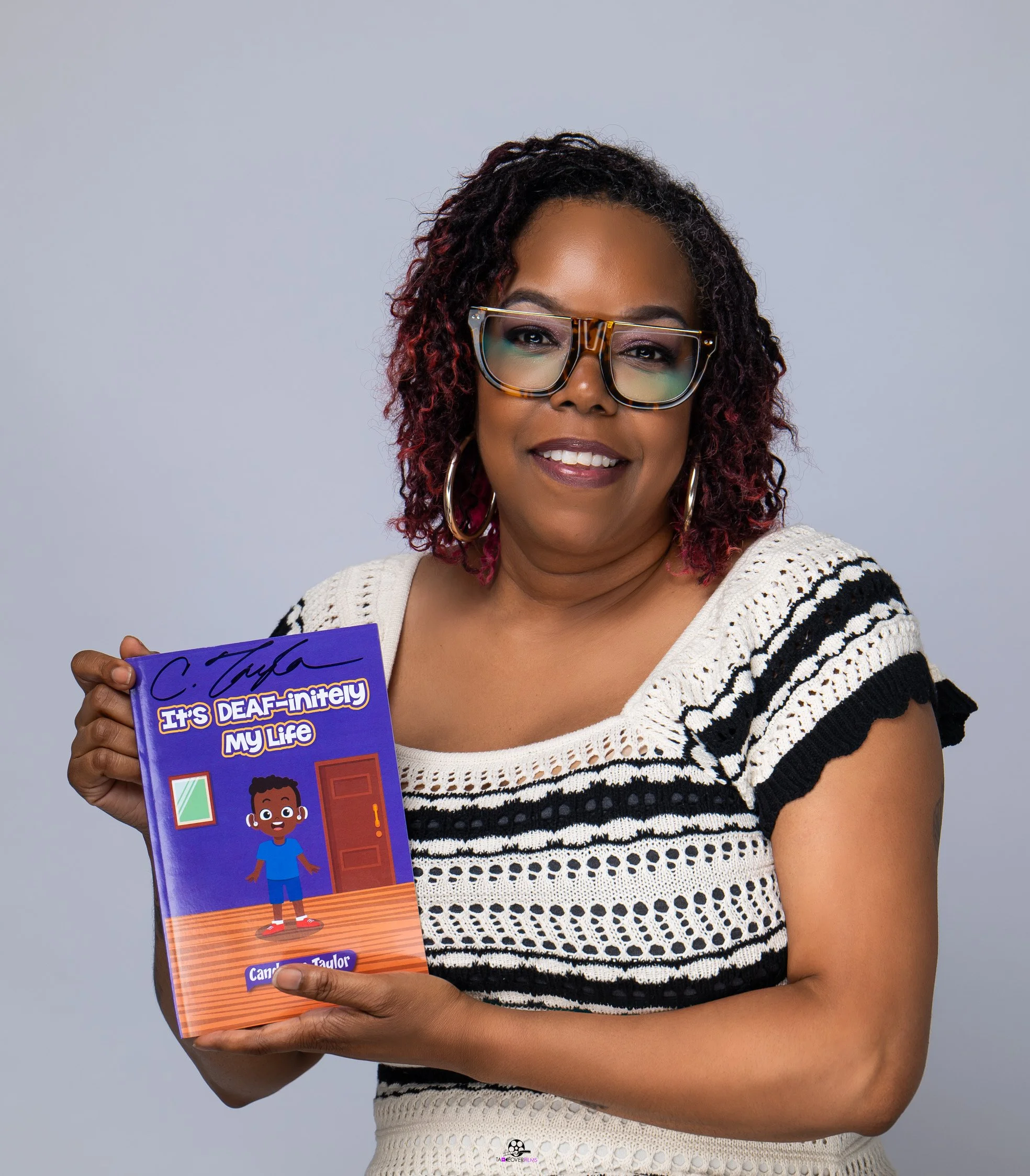 Author of "It's Deaf-initely My Life" holding up her book.