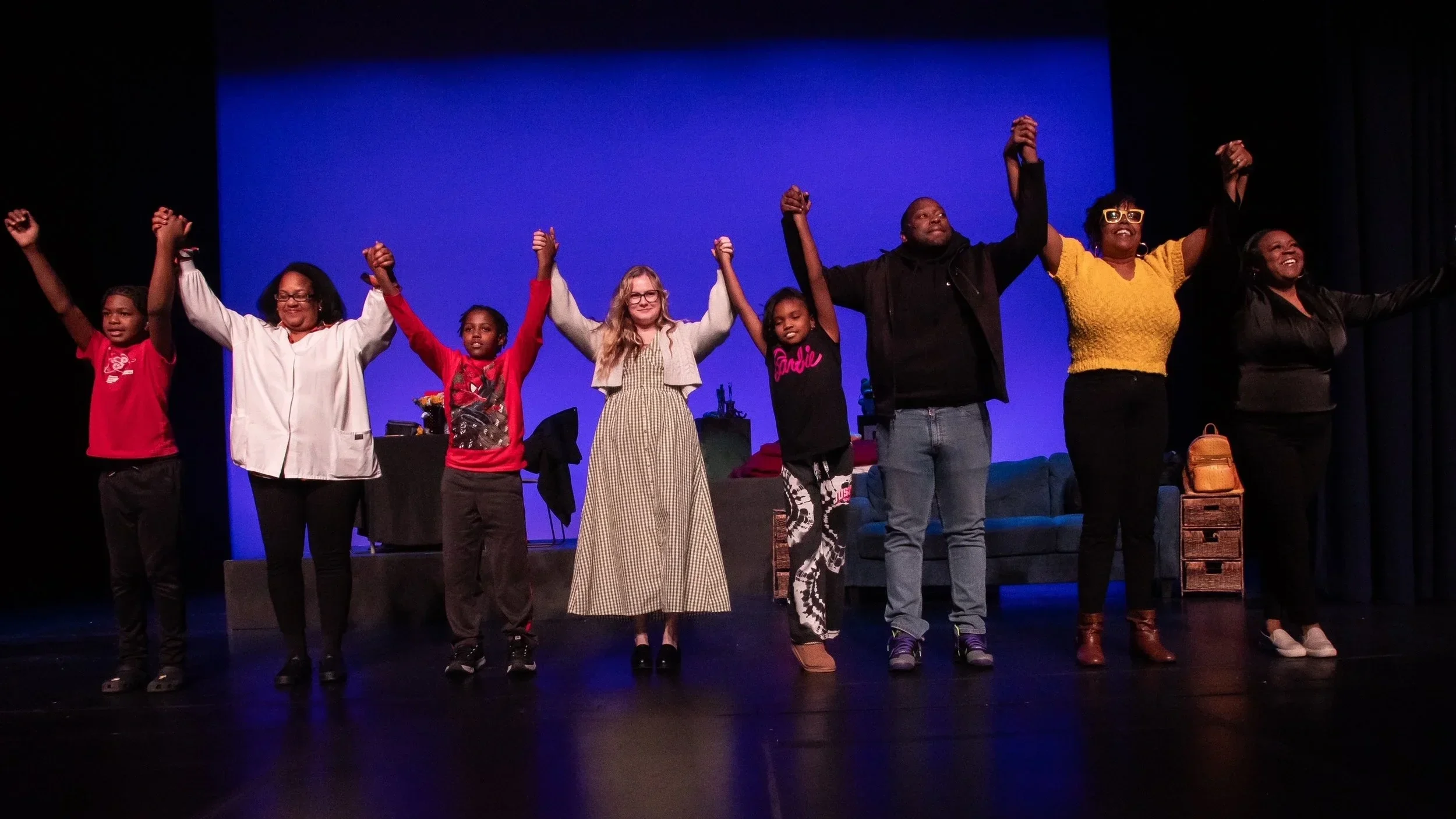 A group of Deaf performers take a bow together on stage after a performance.