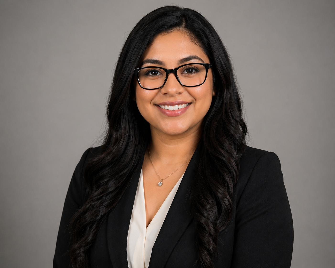 Woman with long black hair wearing a white shirt, and black suit jacket smiling.
