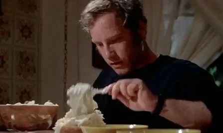 A screen capture from Close Encounters of the Third Kind where Richard Dreyfuss' character, Roy Neary, is crafting mashed potatoes into the Devil's Tower national monunment