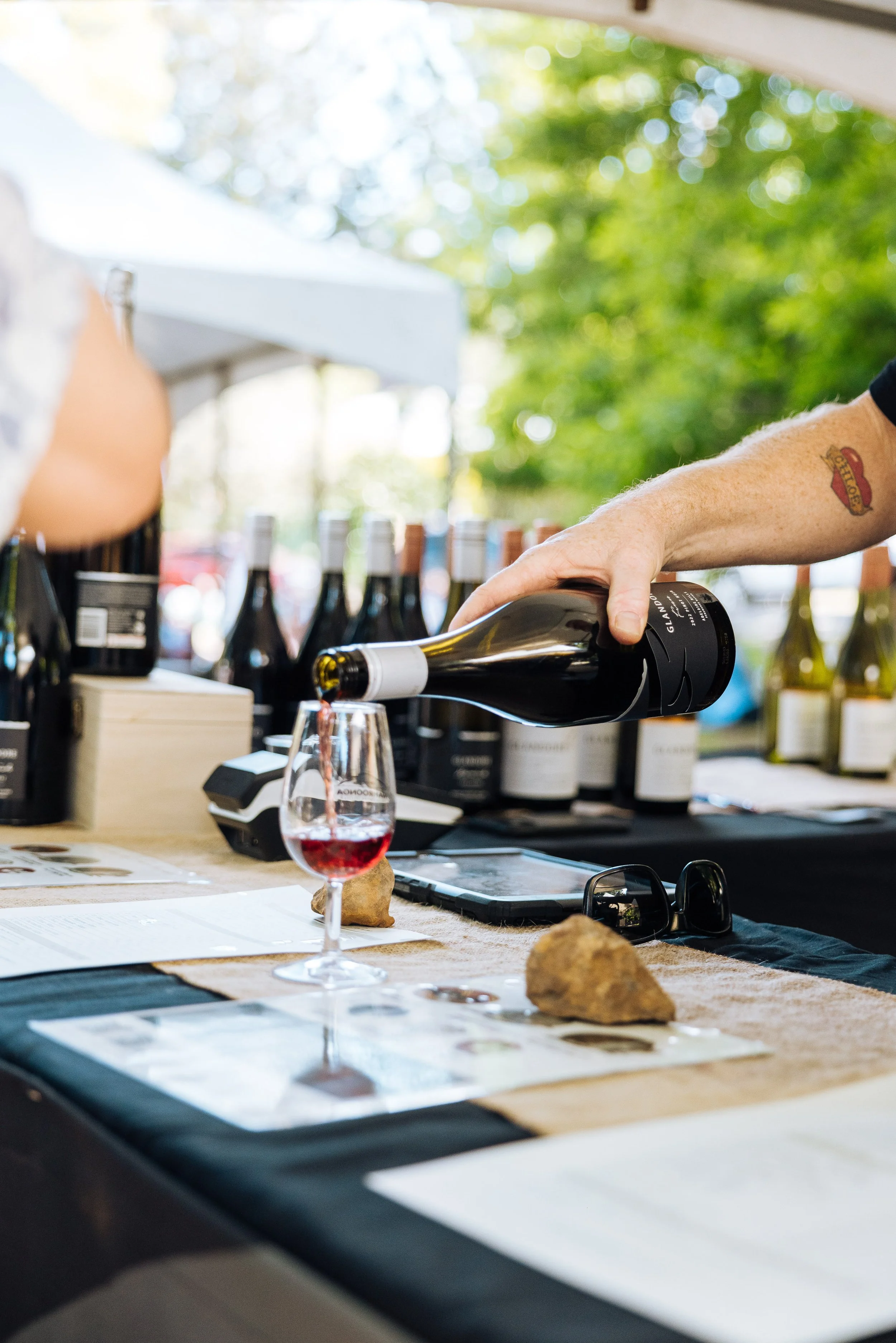 Wine stand at food festival, wine glass on counter with wine being poured in.