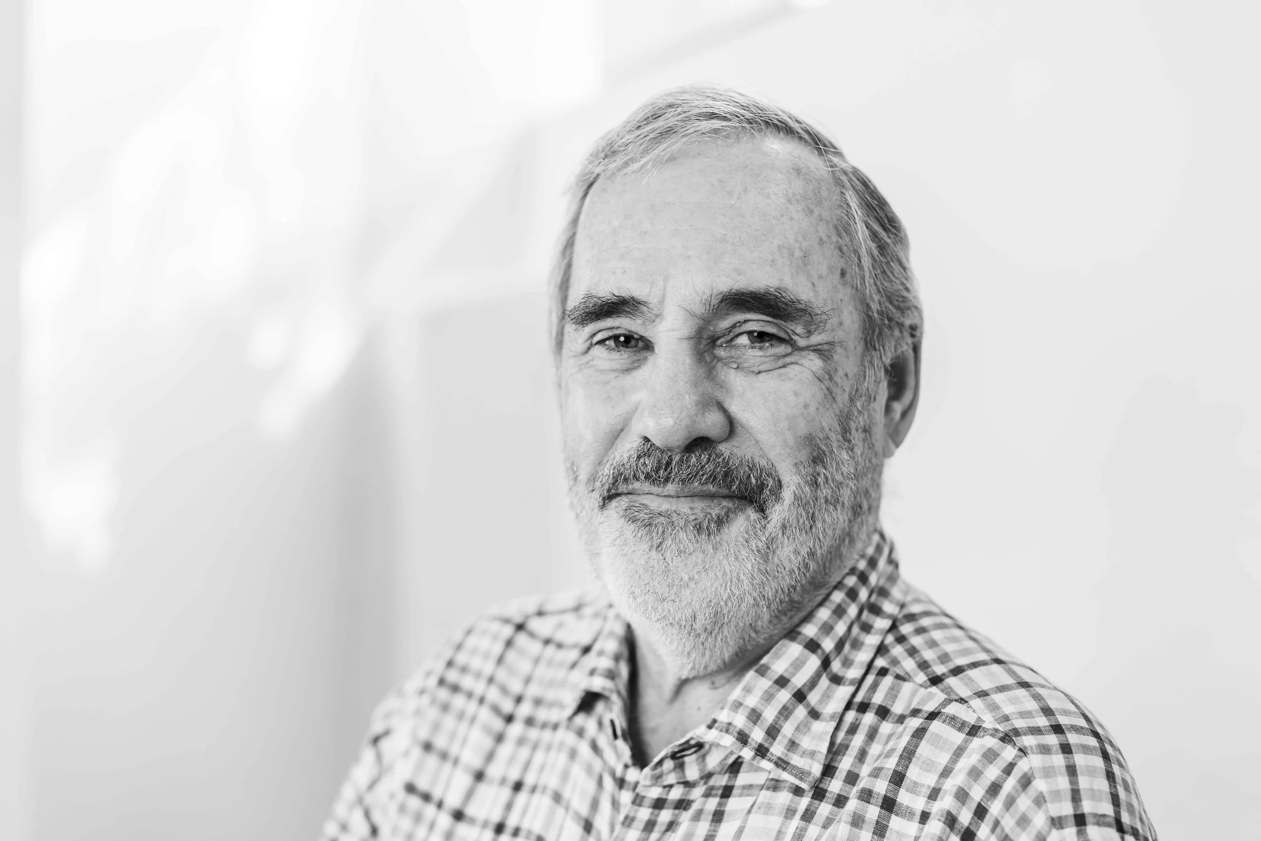 black and white image of man aged 70 wearing a plaid shirt