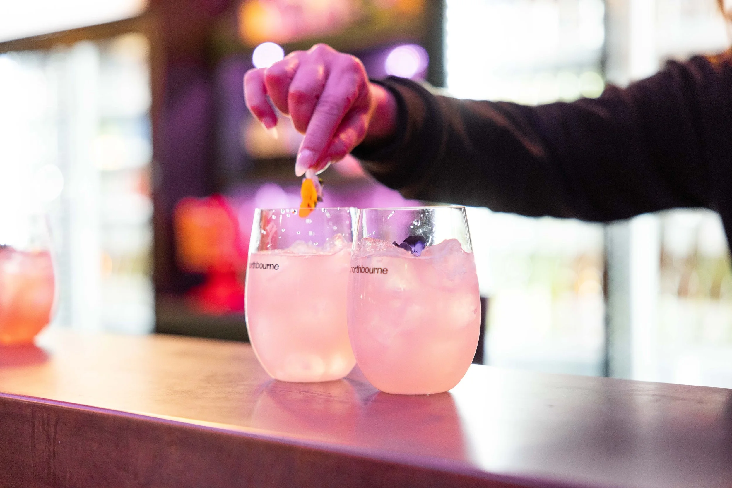 two glasses with Northbourne branding filled with ice and a drink