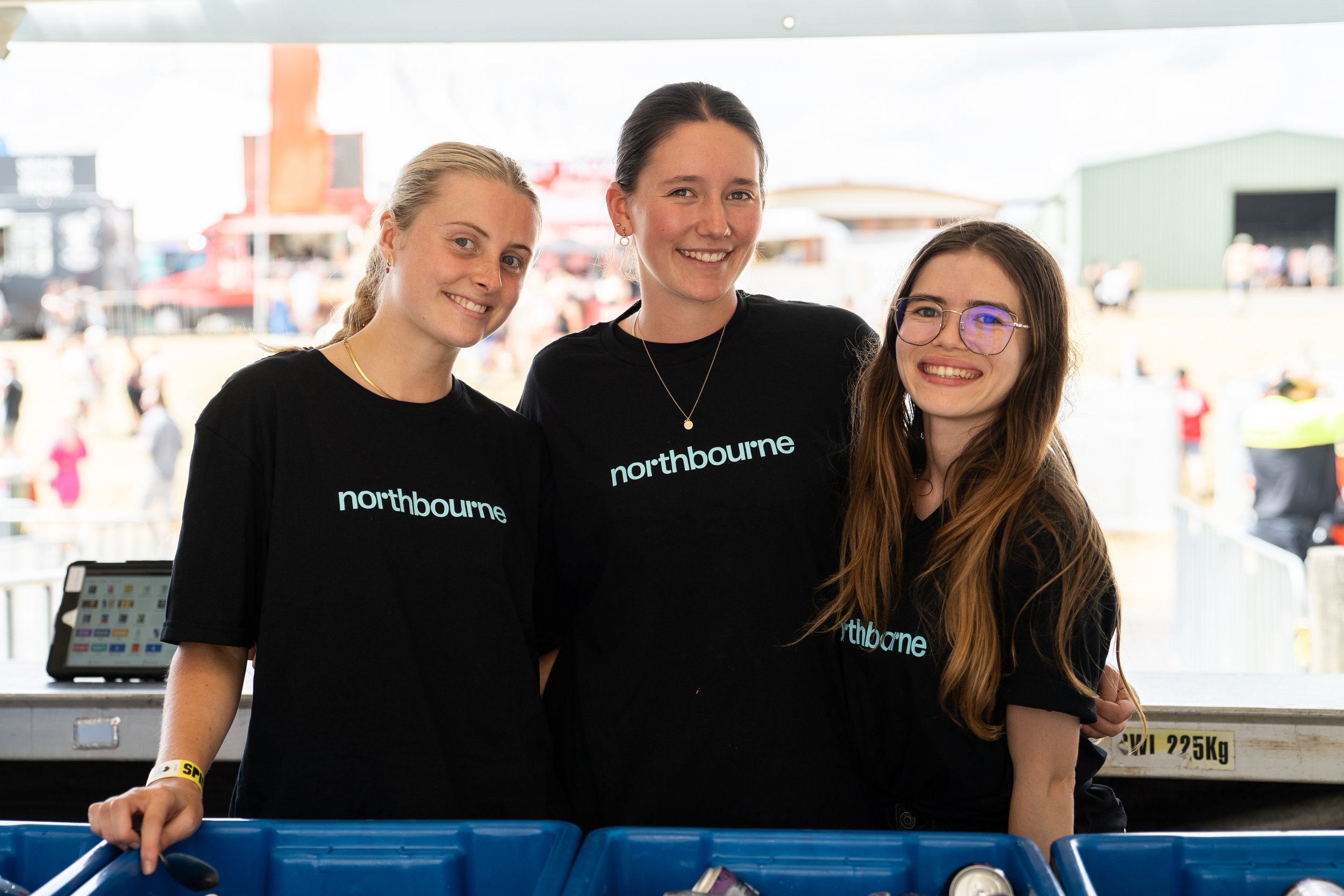 3 girls wearing Northbourne staff shirts at a music festival bar