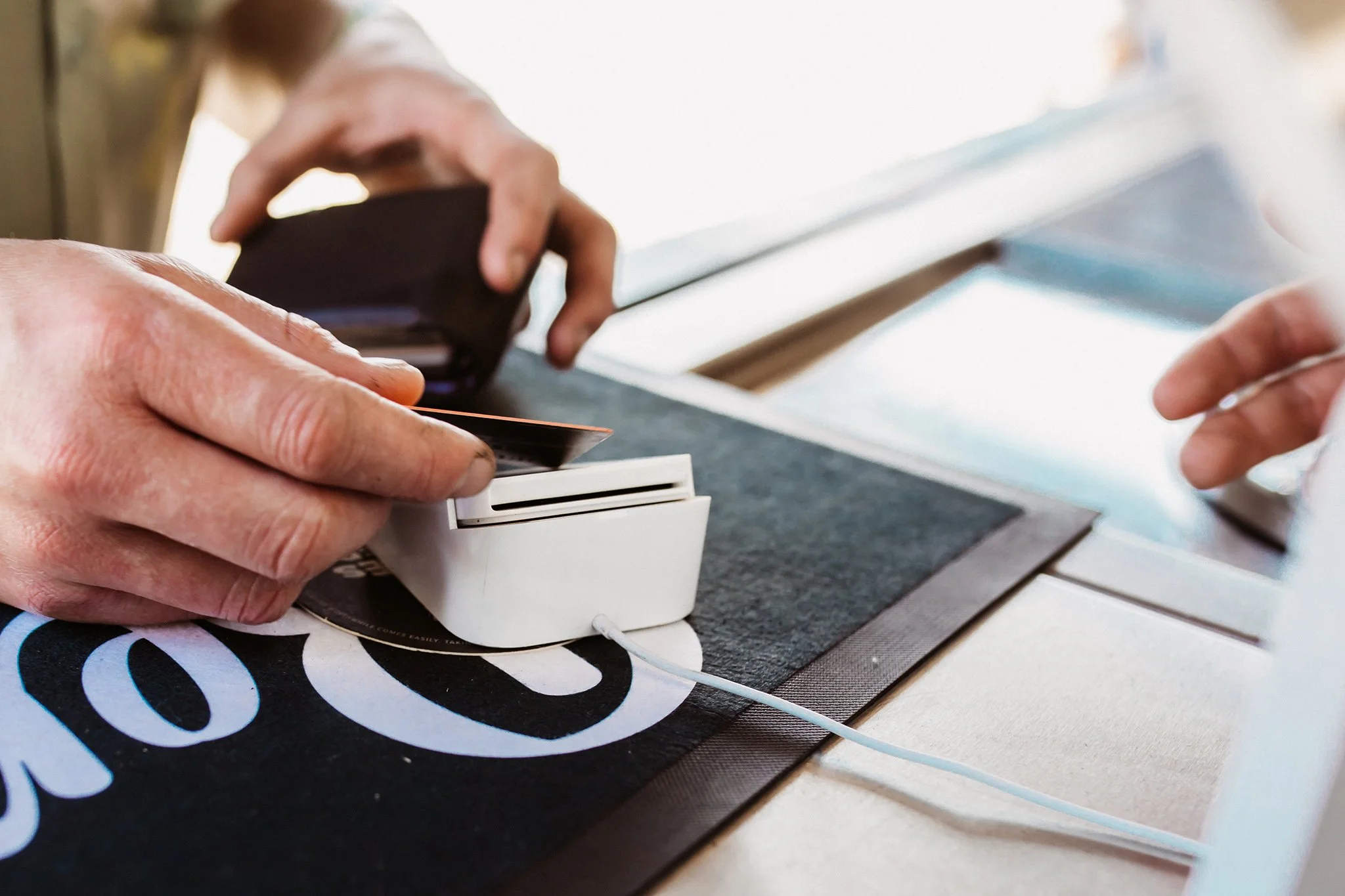 a hand using a square POS system with a credit card
