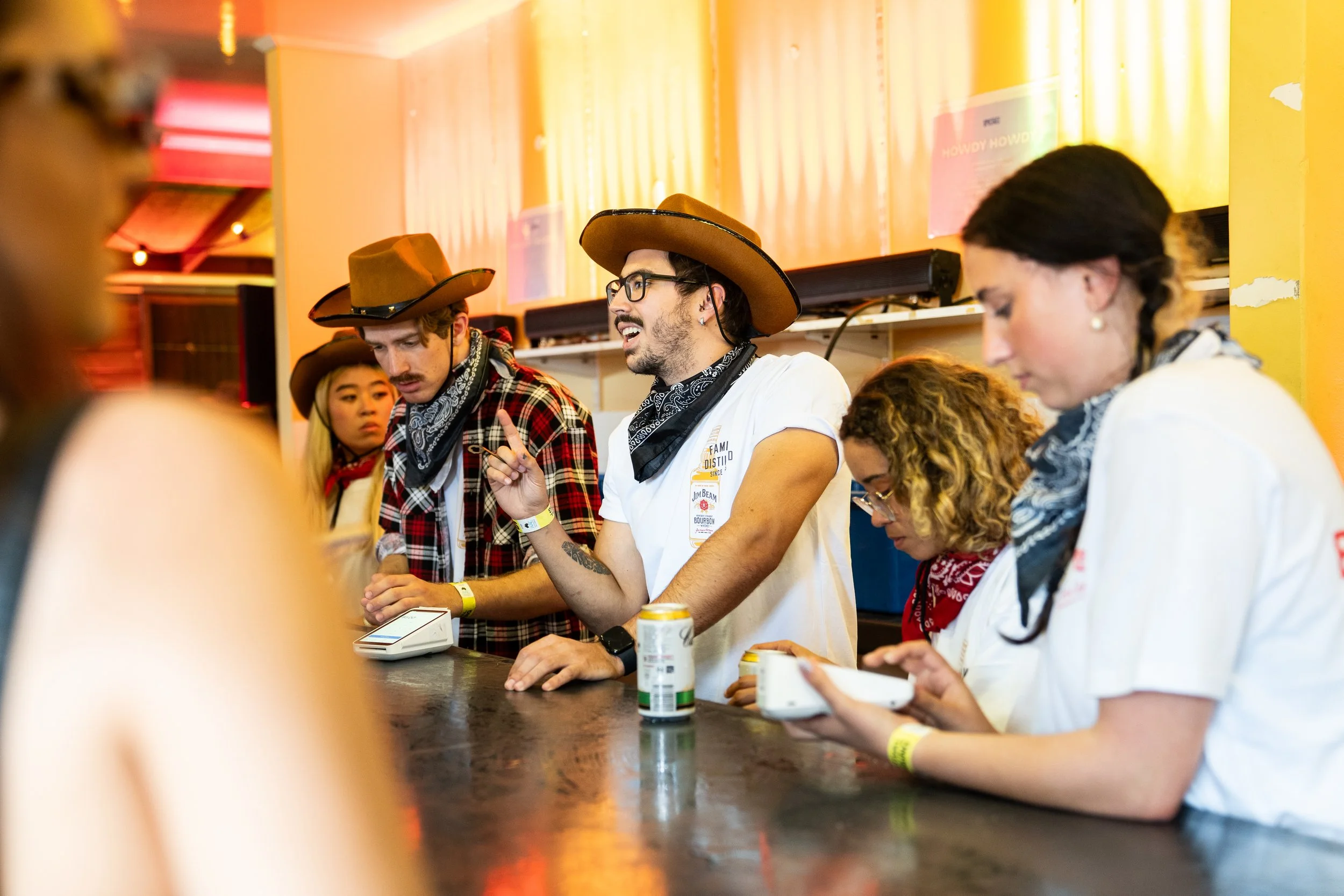 Staff behind a bar dressed up in cowboy clothes.