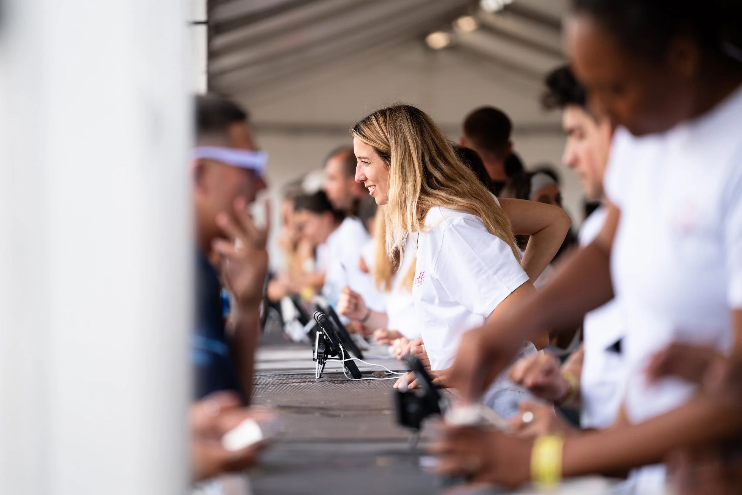Multiple people in white uniforms engaging at an event, with some wearing protective glasses, microphones on the table, and a woman in the center smiling.