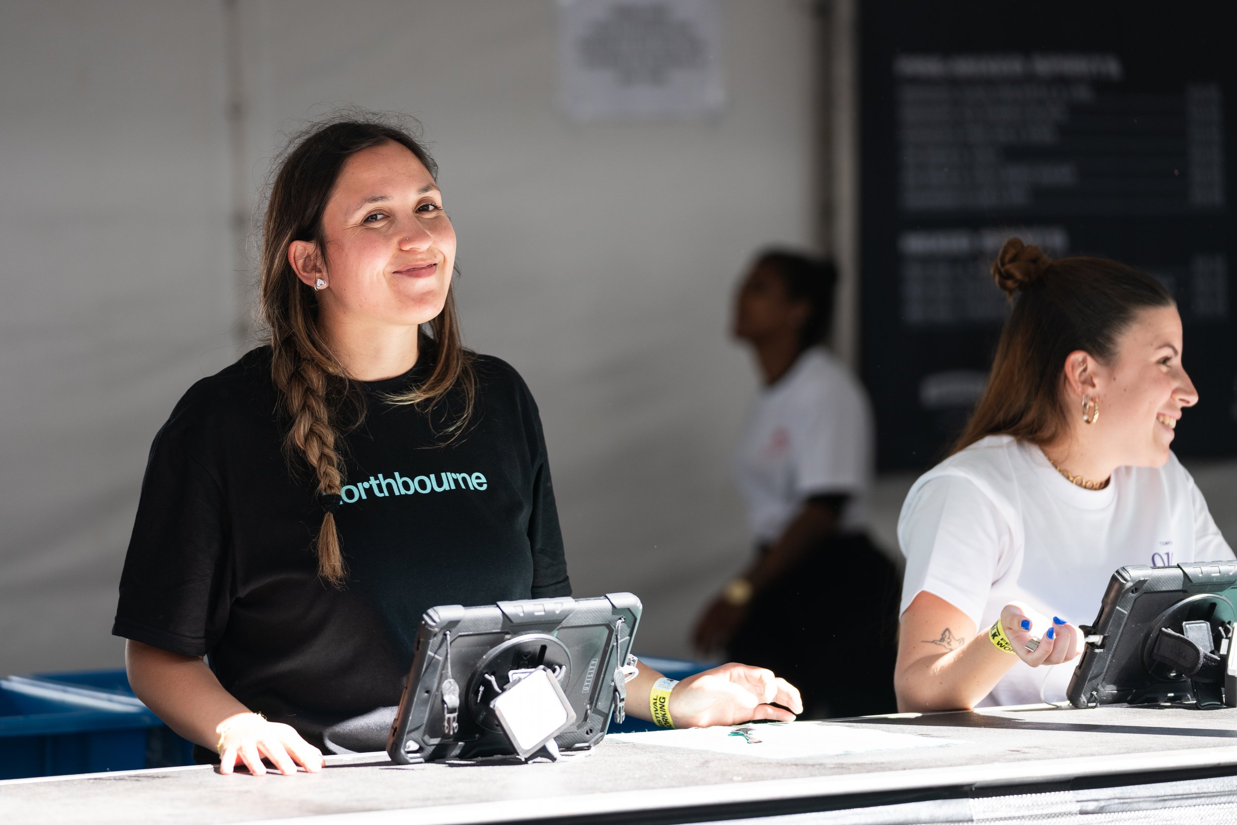 girl smiling wearing a black northbourne branded shirt standing behind a bar
