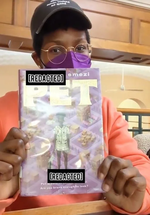 Kenyatta holding a book that reads "PET" by Akwaeke Emezi