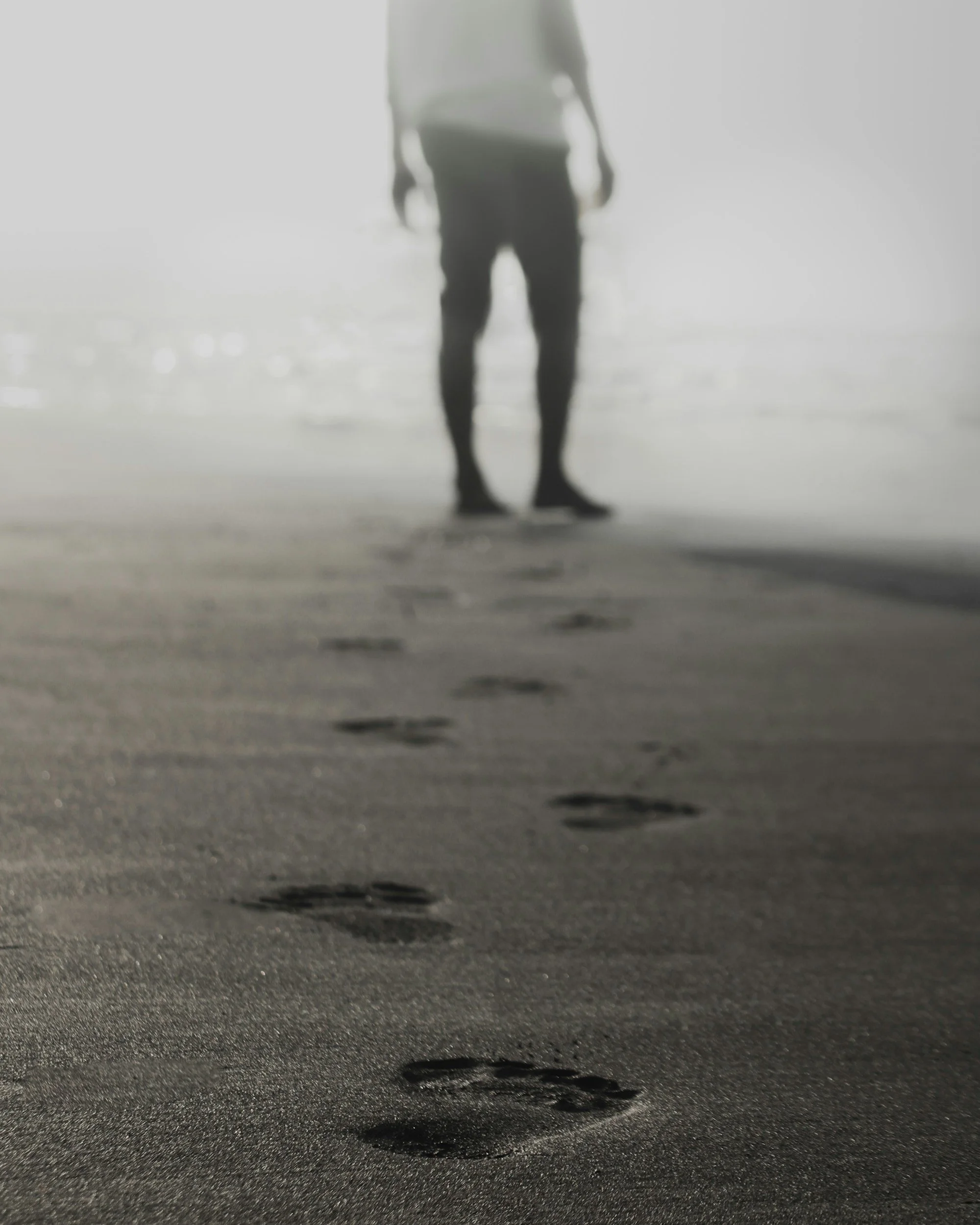Person walking on beach leaving footprints