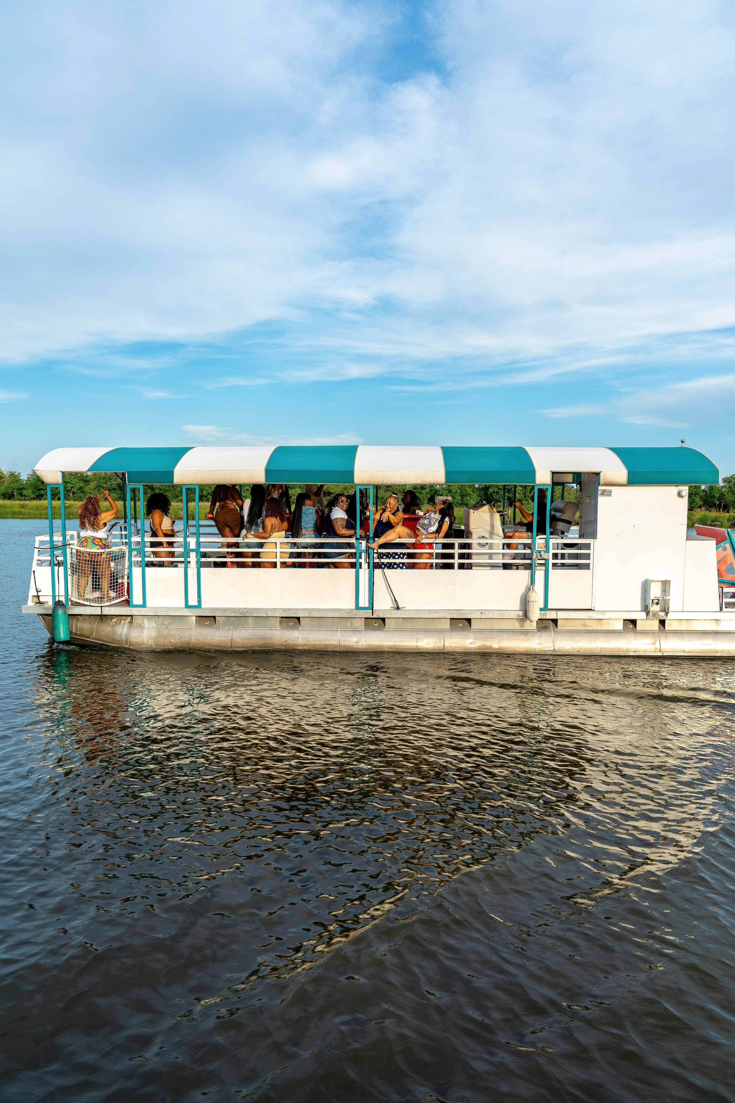 People enjoying a boat ride on a river with a cloudy sky above.
