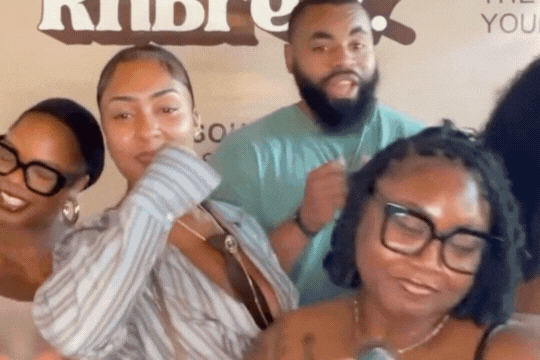 Crowd of people socializing at an indoor gathering or event, some holding drinks, with a warm, lively atmosphere.