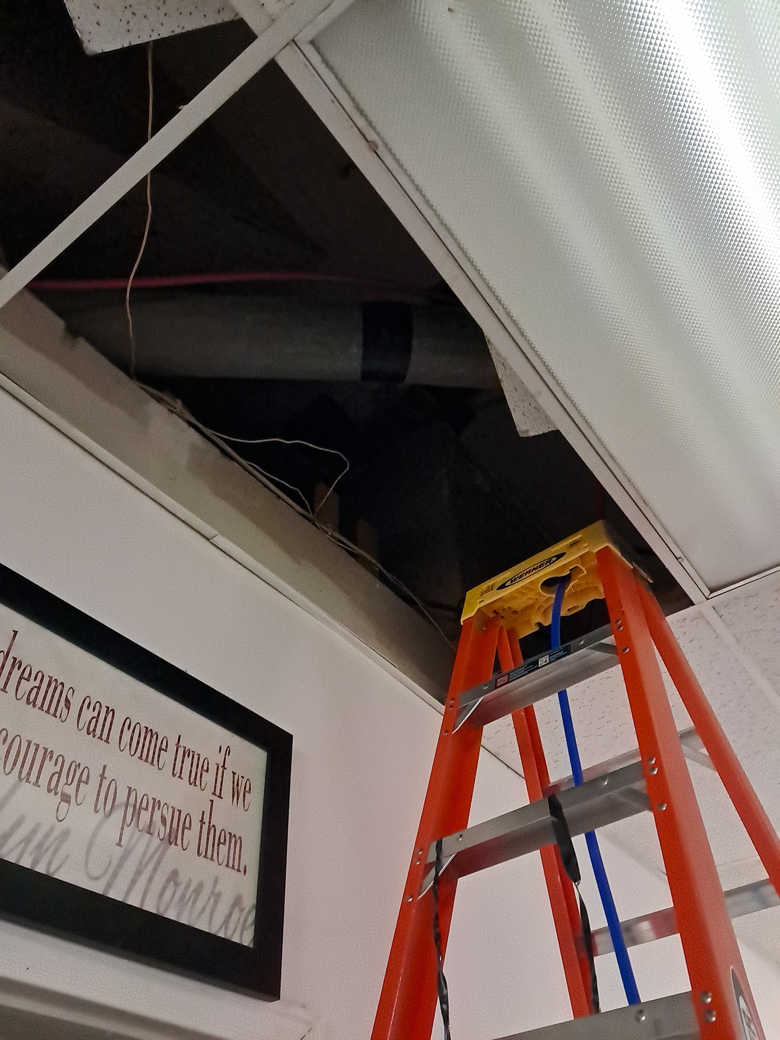 Handyman running water line inside of drop ceiling