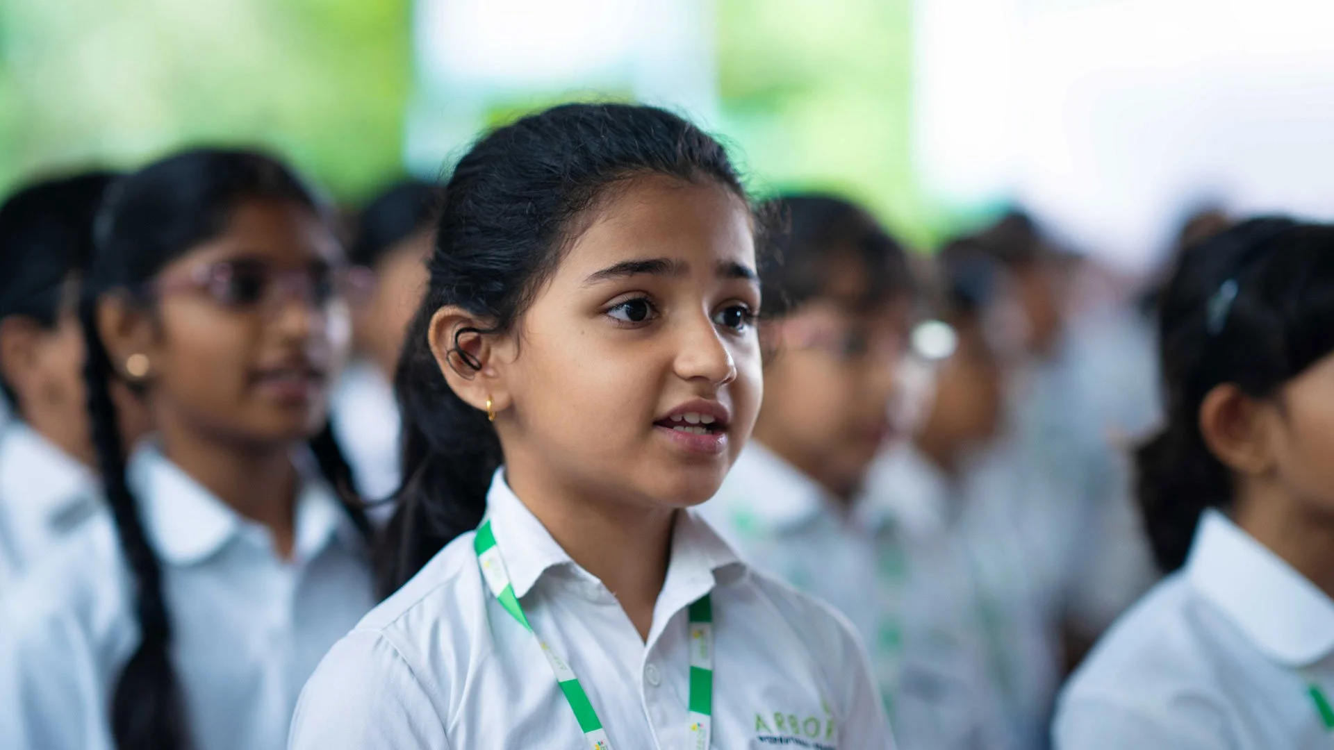 Group of school children in uniform listening attentively.