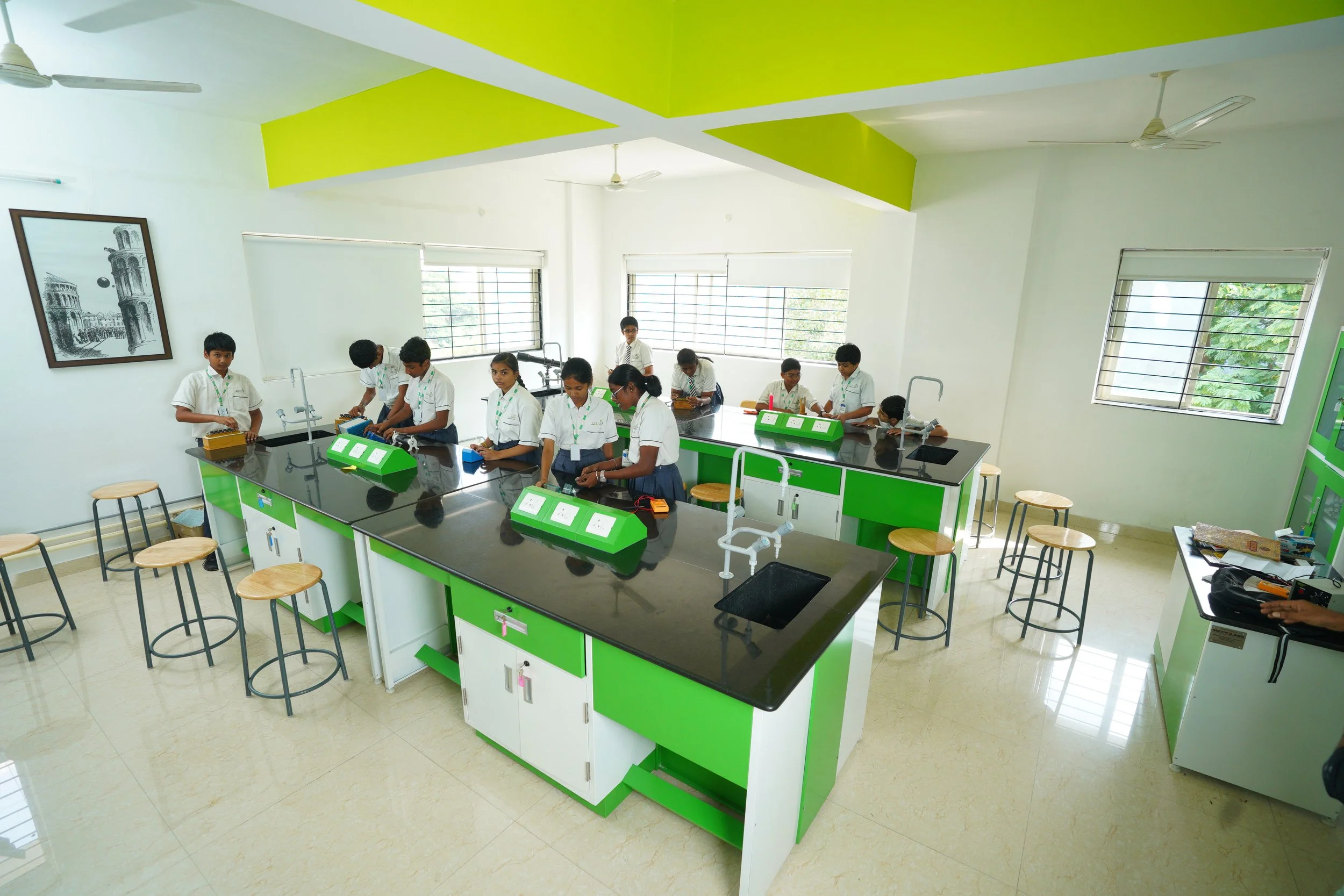 Students performing experiments in a brightly lit science lab with green and white decor, featuring modern lab equipment and stools.