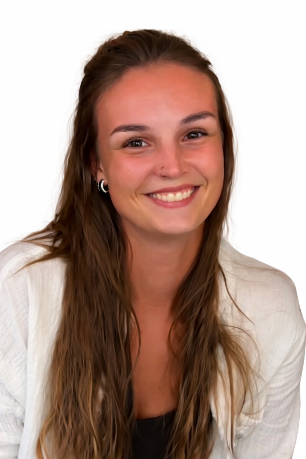 A woman with shoulder-length light brown hair and hazel eyes smiling at the camera in a room with a bookshelf and a bouquet of flowers in a vase in the background.