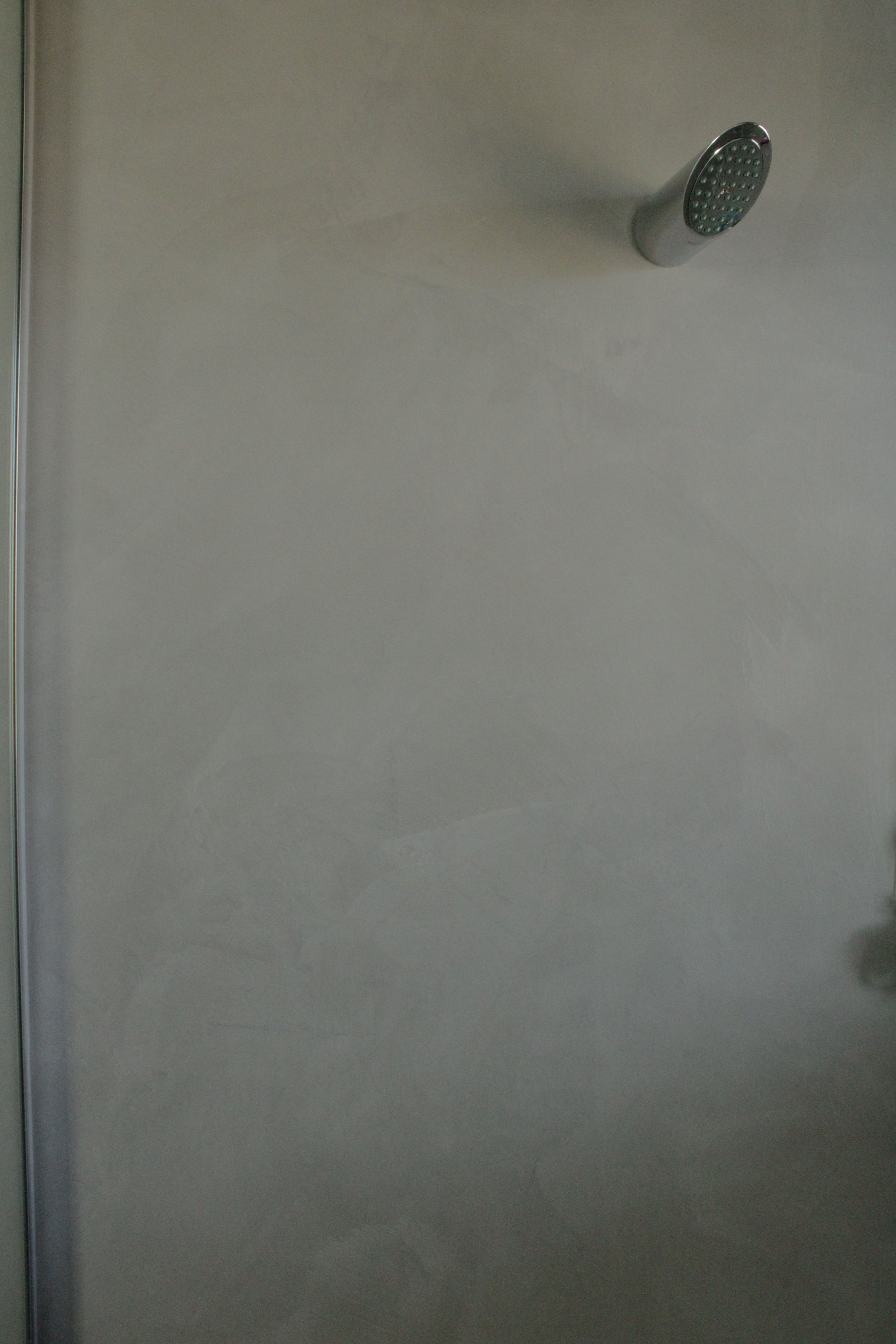 A plain white ceiling with a silver showerhead attached, positioned towards the top right corner of the image.