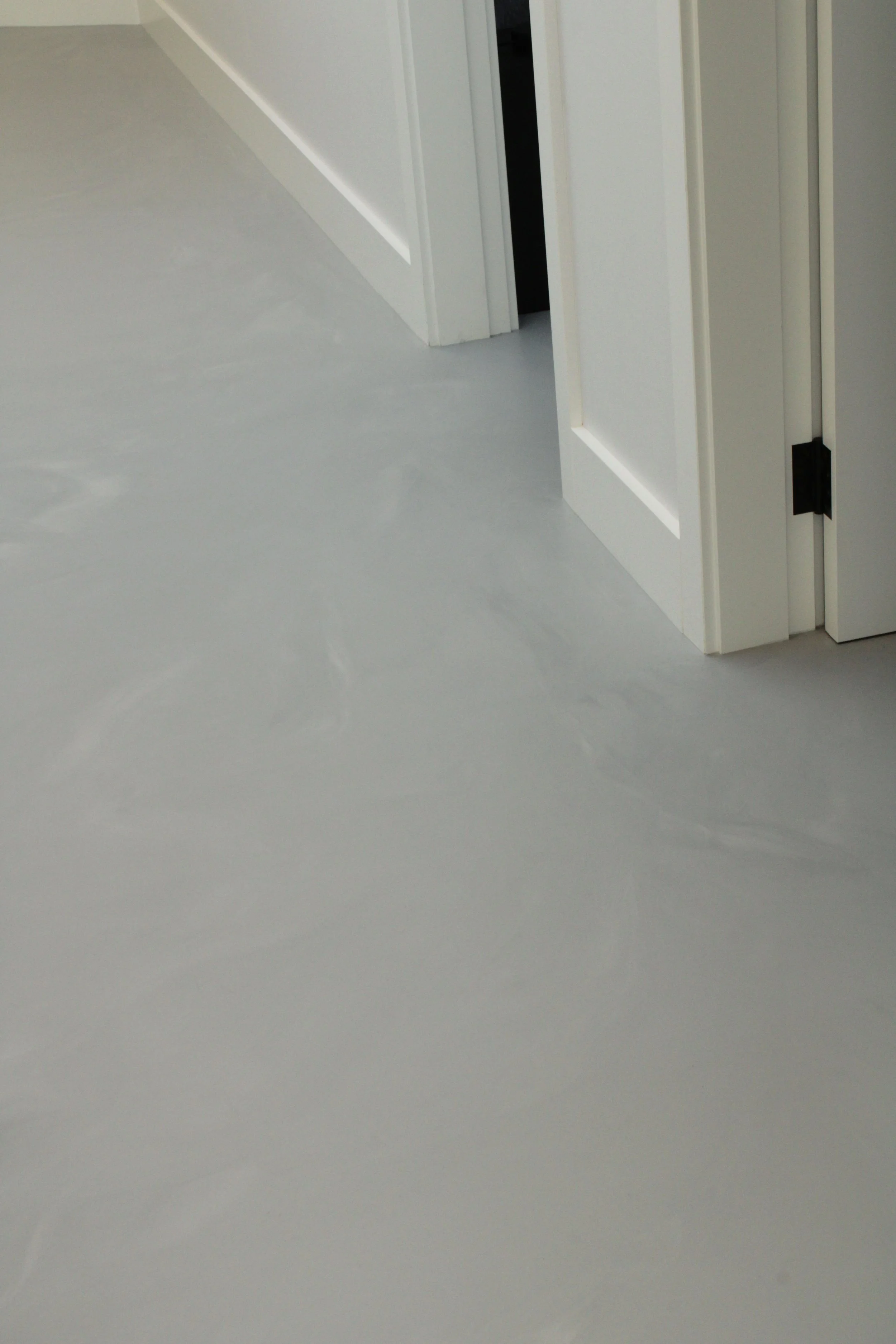 Close-up of white doors and gray floor in a modern interior space.