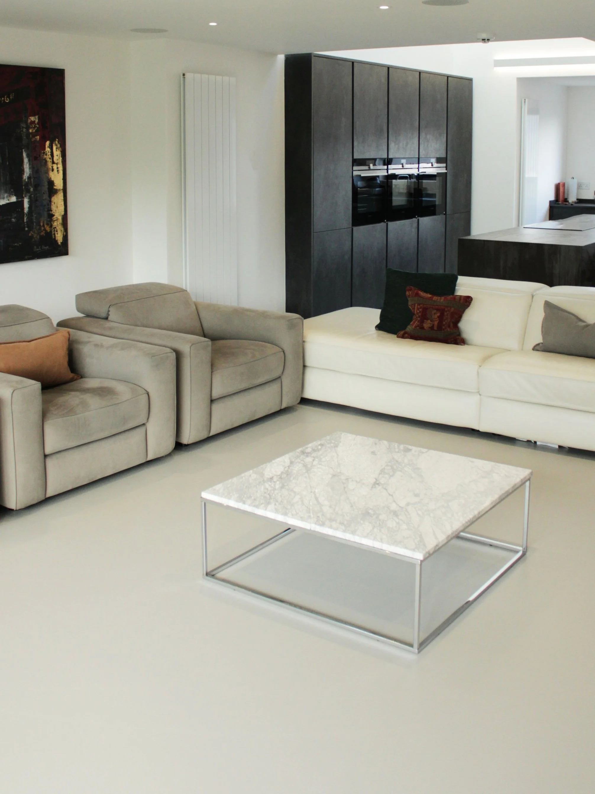 Modern living room with beige sofa, black and dark gray cabinet, and a marble coffee table with a metal frame.