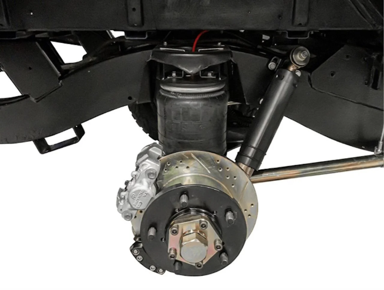 Close-up of a vehicle's wheel assembly with upgraded disc brakes, AirBag Suspension system and axle components visible.