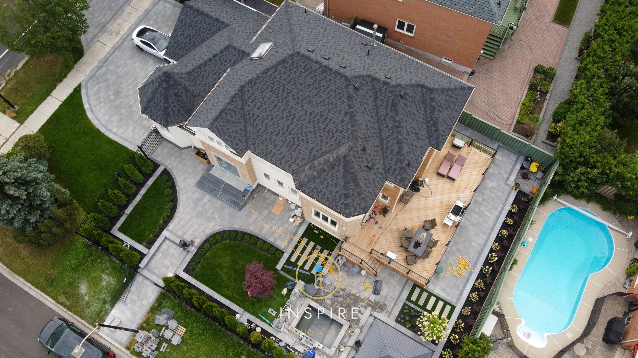 Custom design and build landscaping in progress with all Unilock Windermere pavers, custom pressure treated deck, artificial turf accents and koi pond with waterfall feature