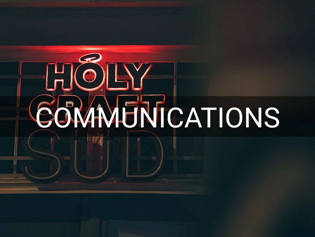 Neon-Schriftzug mit den Wörtern „HOLY CRAFT“ und „COMMUNICATIONS“ in rotem und weißem Licht.