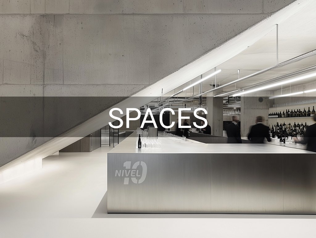 Modernes Bar-Interieur mit Betonwänden, einem langen Metalltresen und mehreren Flaschen im Hintergrund. Das Wort "SPACES" ist in der Mitte des Bildes sichtbar.