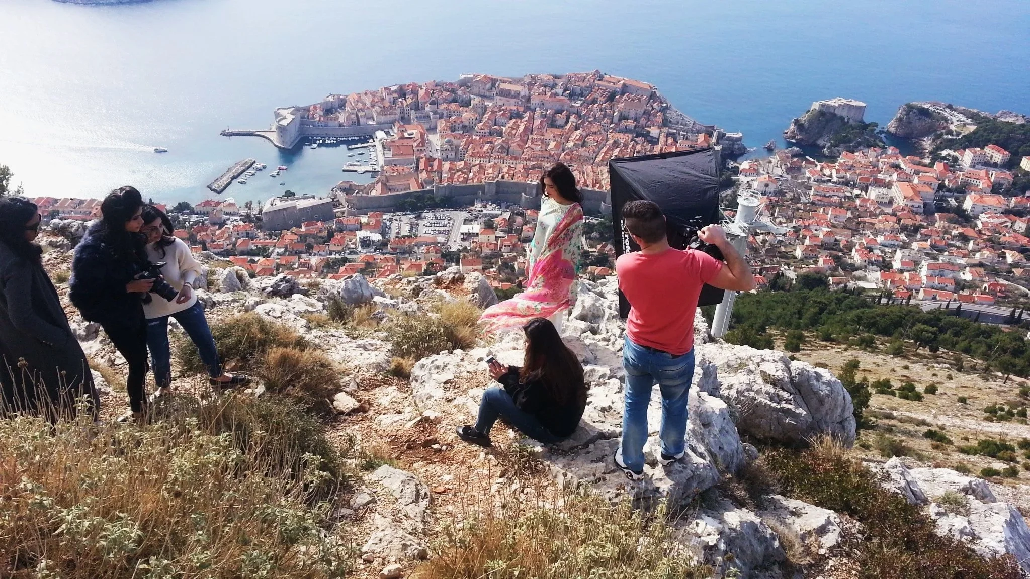 Photography set with a model on a hill above Dubrovnik, Croatia, with panoramic view of the city in the background