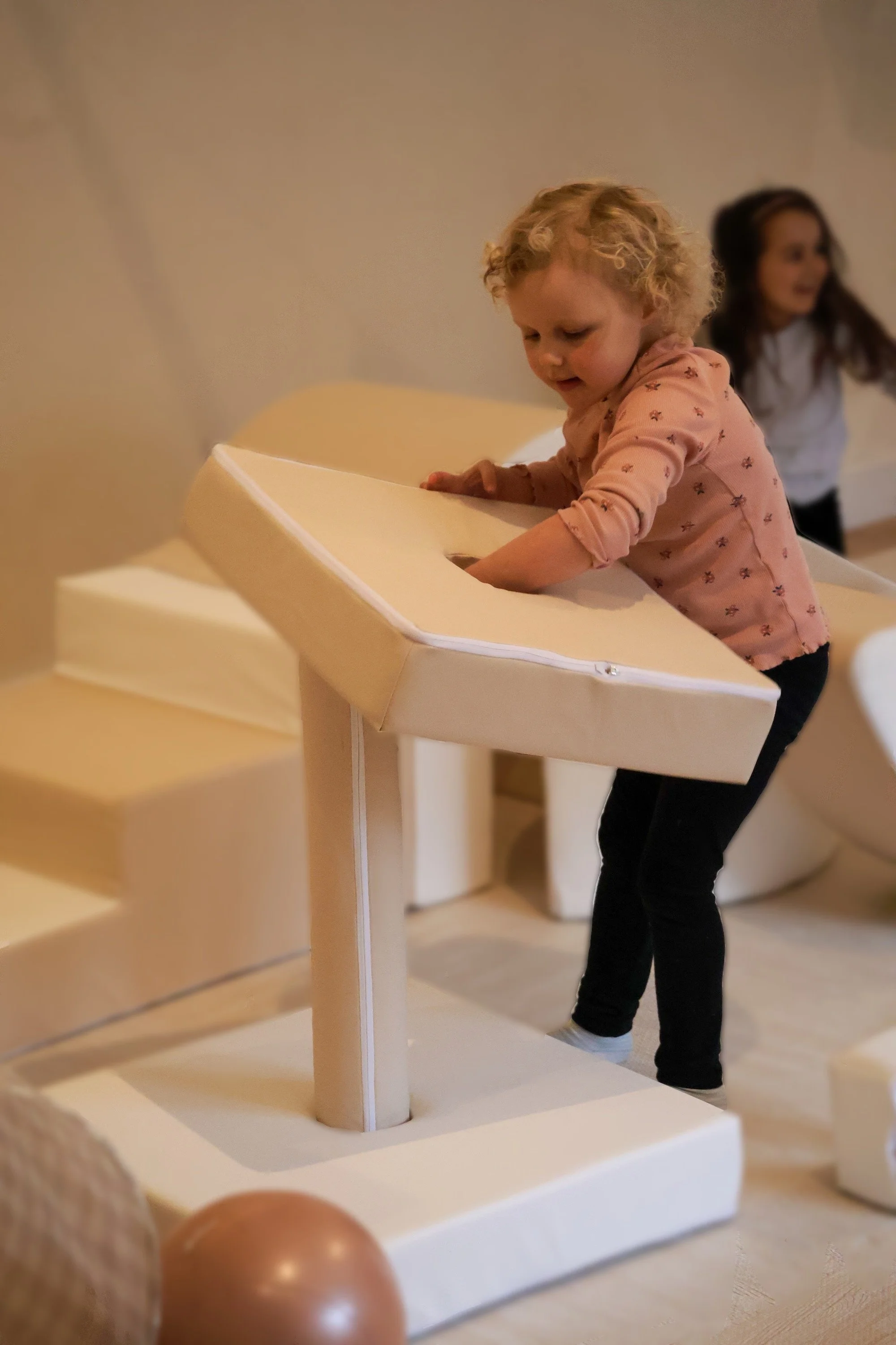 Child playing with soft play equipment indoors.