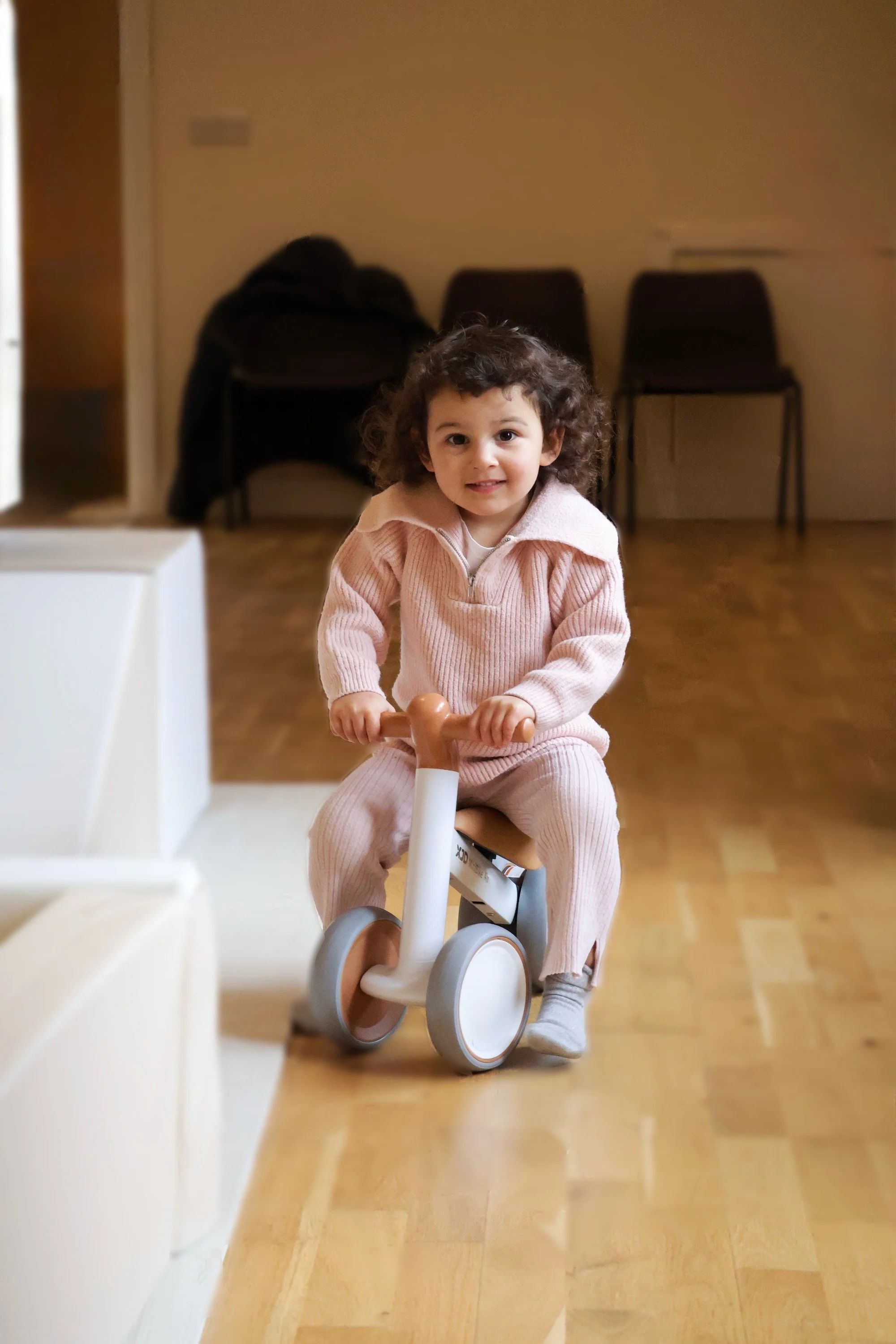 Child riding a small balance bike indoors