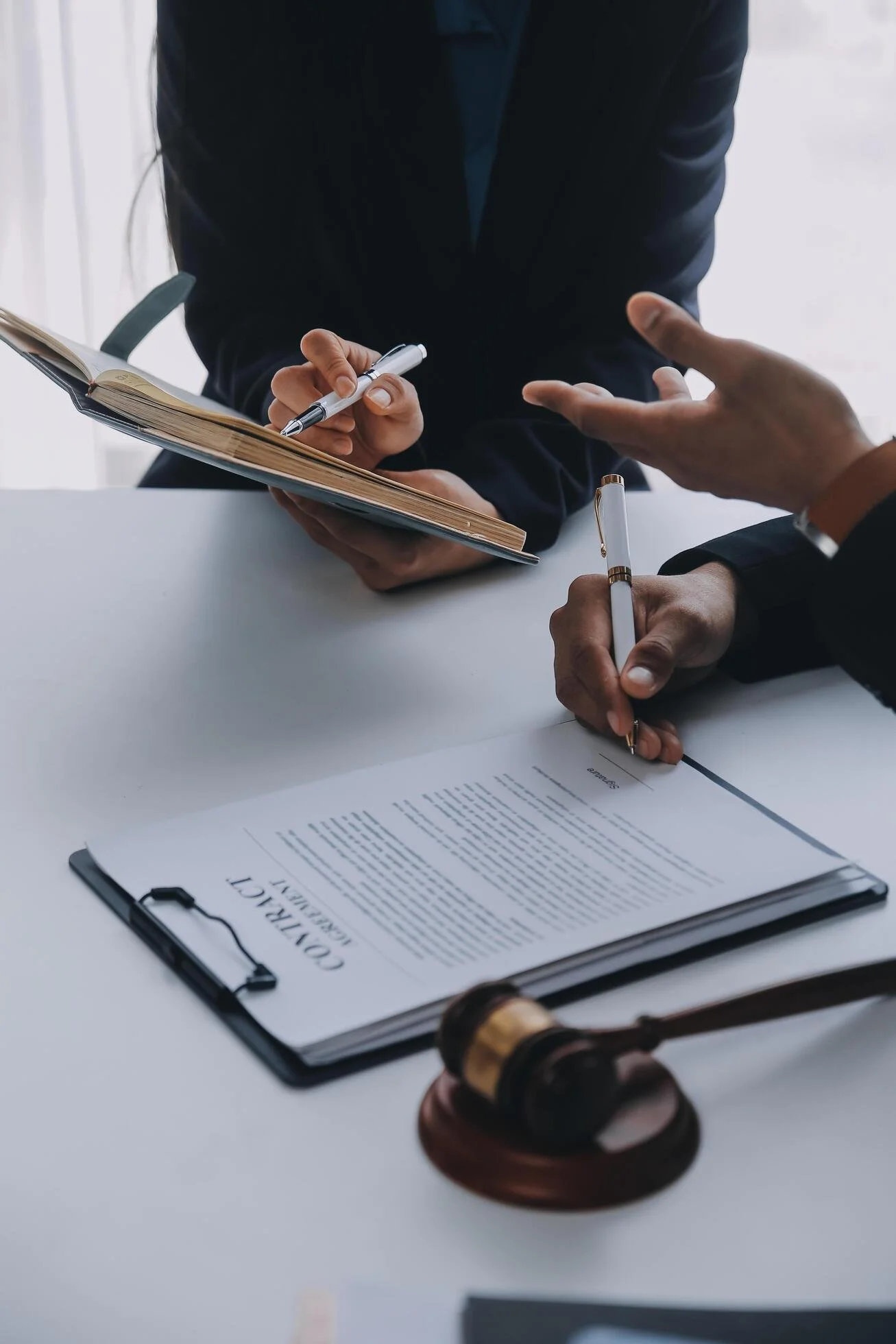 Two people sitting at table reviewing a contract and taking notes.
