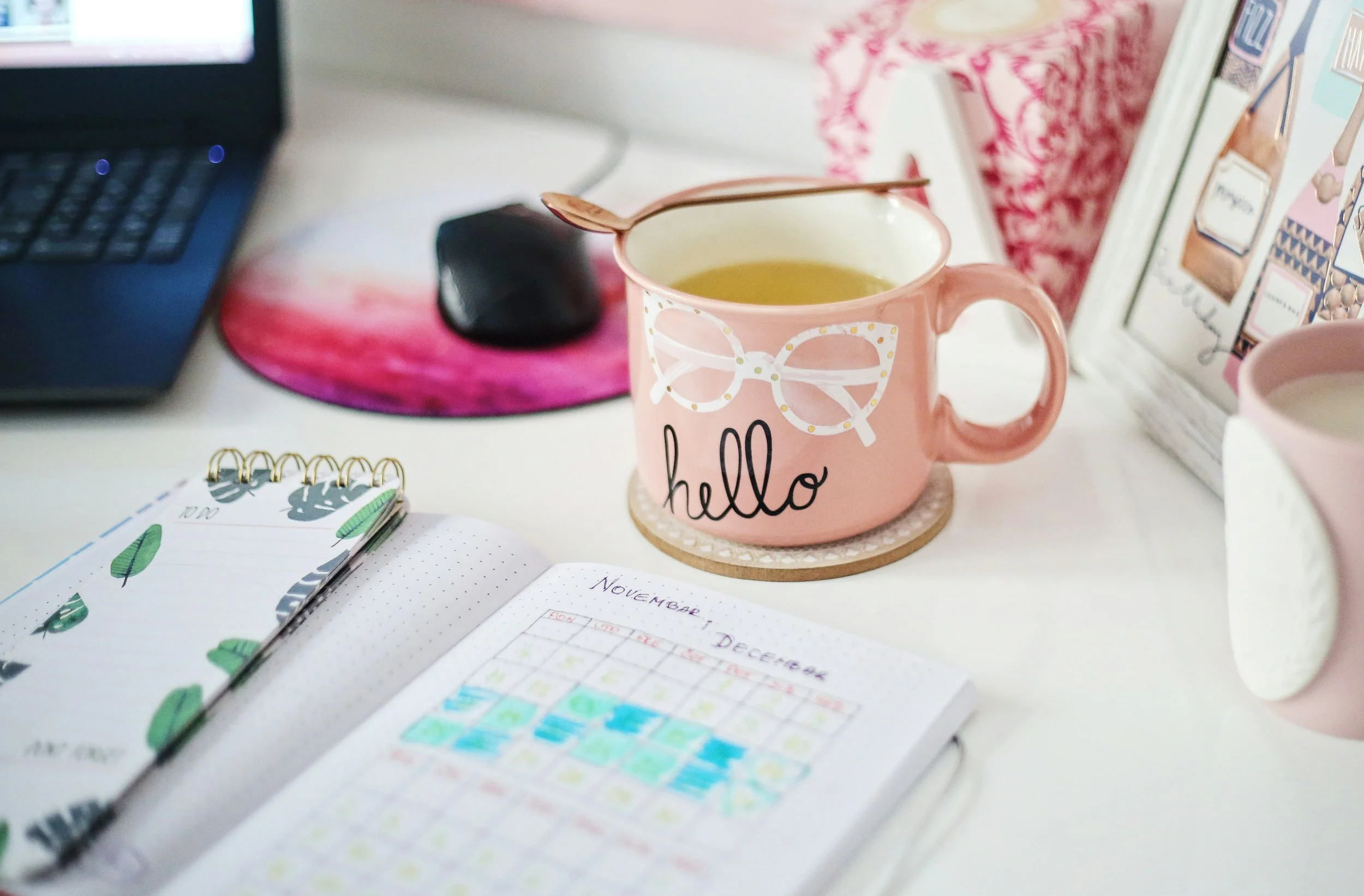 Desk with pink mug, planner and laptop