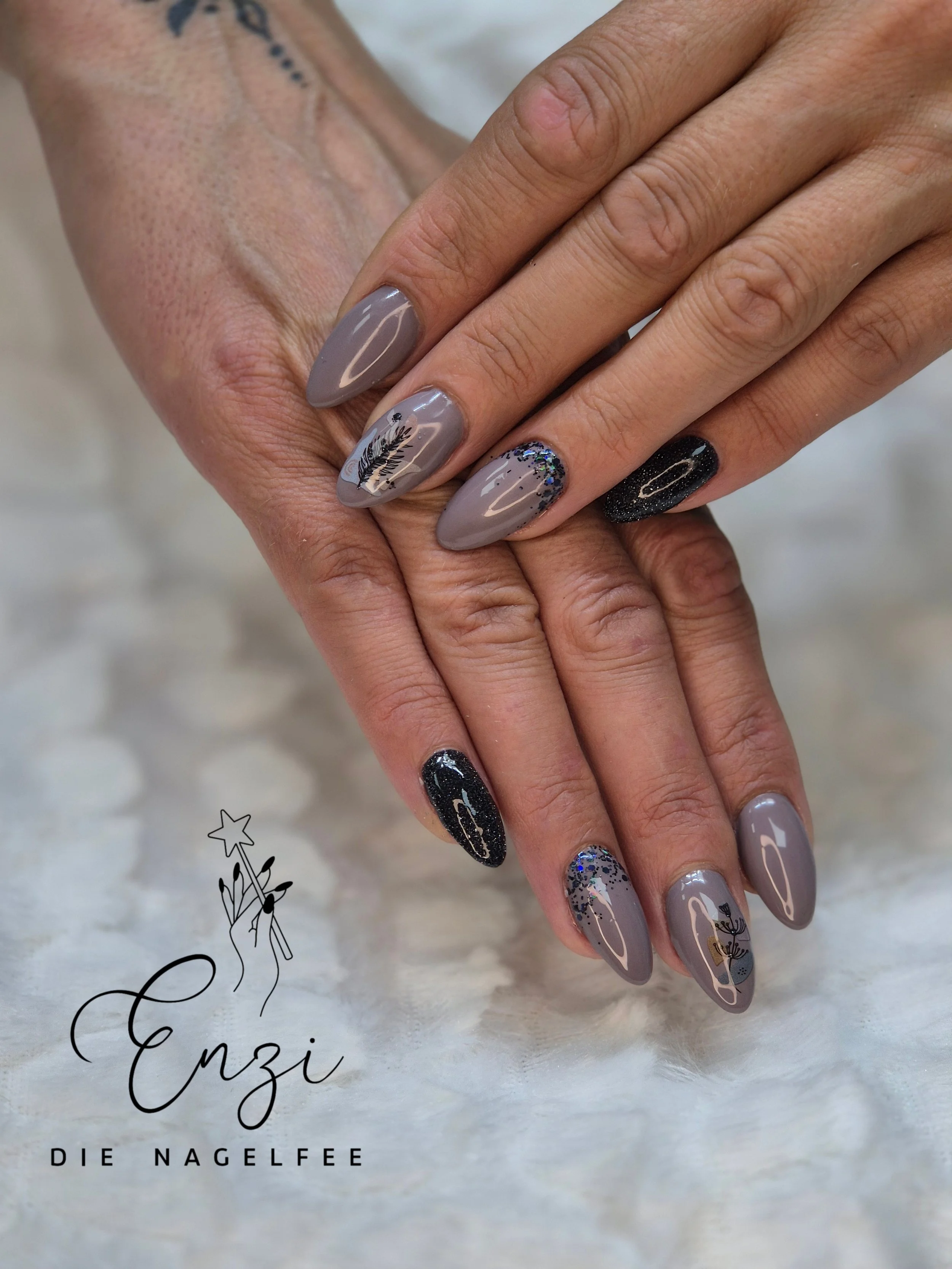 Nägel mit lackiertem Design in Grau, Schwarz und Glitzer, mit Blumen- und Blättermotiven.