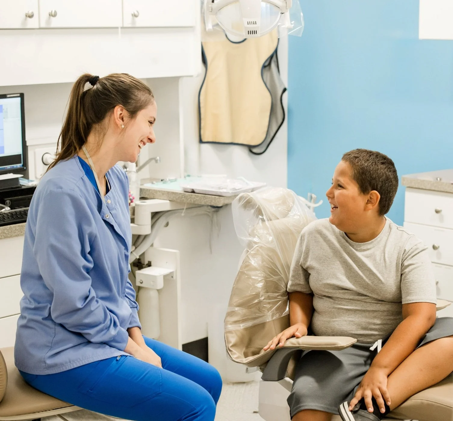 Dentist and child patient smiling at each other in a dental office.