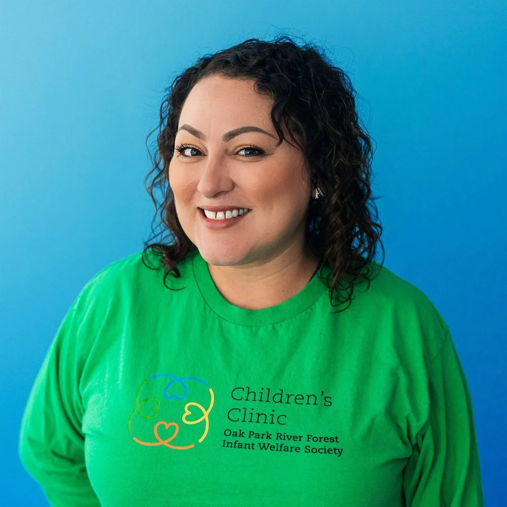 Woman in a green shirt with 'Children's Clinic Oak Park River Forest Infant Welfare Society' logo, smiling against a blue background.