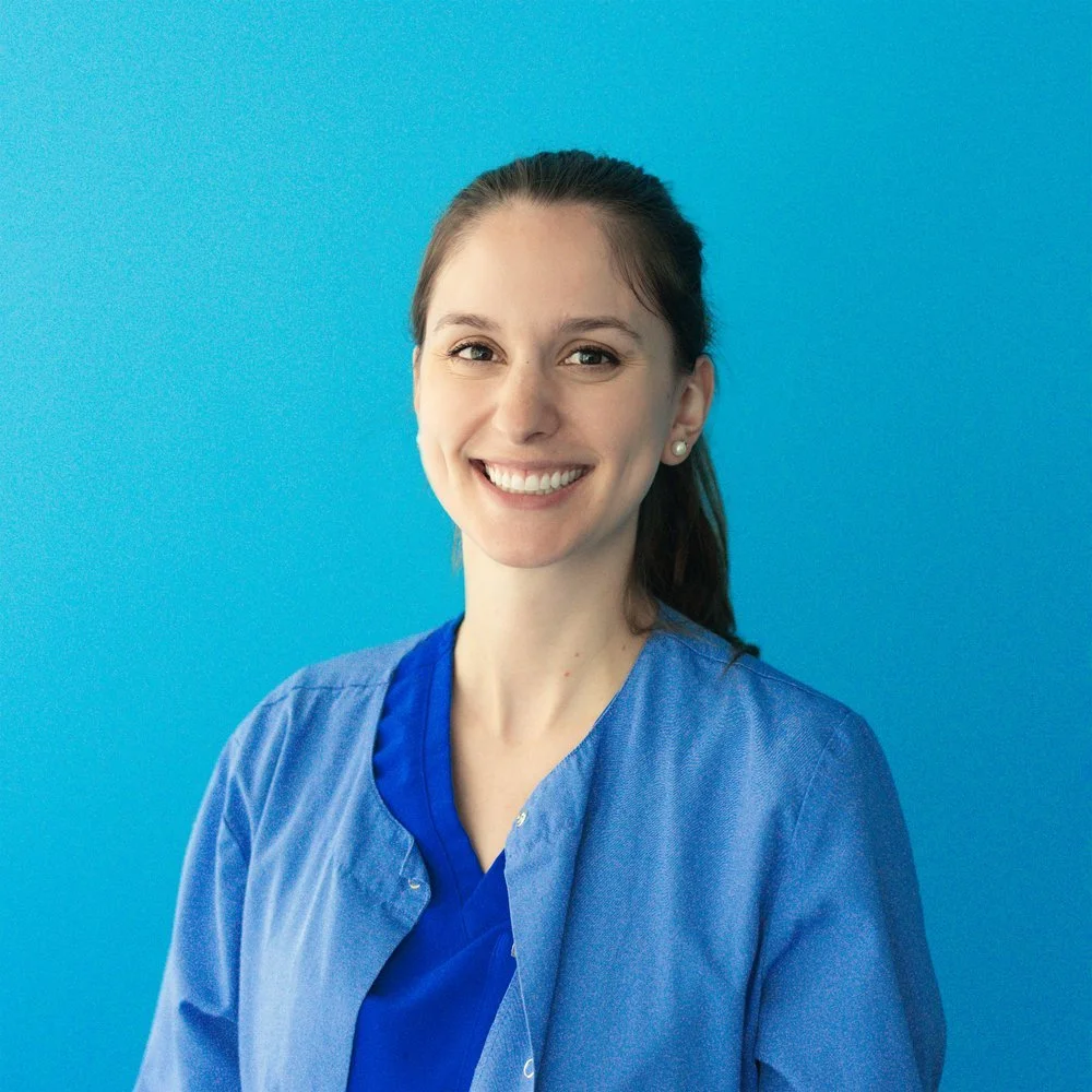 Smiling person in blue medical scrubs against blue background