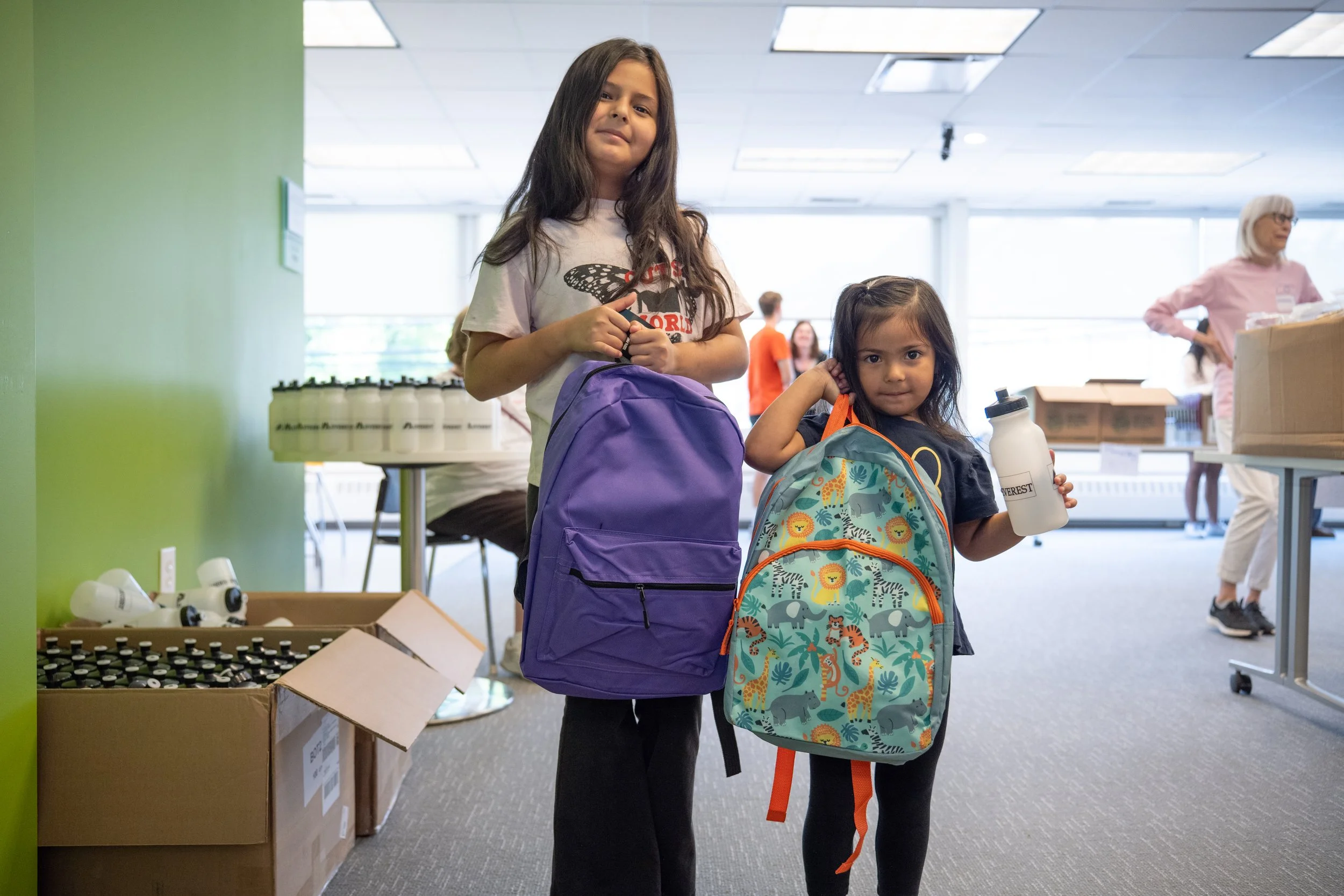 two young girls holding their new backpacks as part of the back pack giveaway for OPRF IWS
