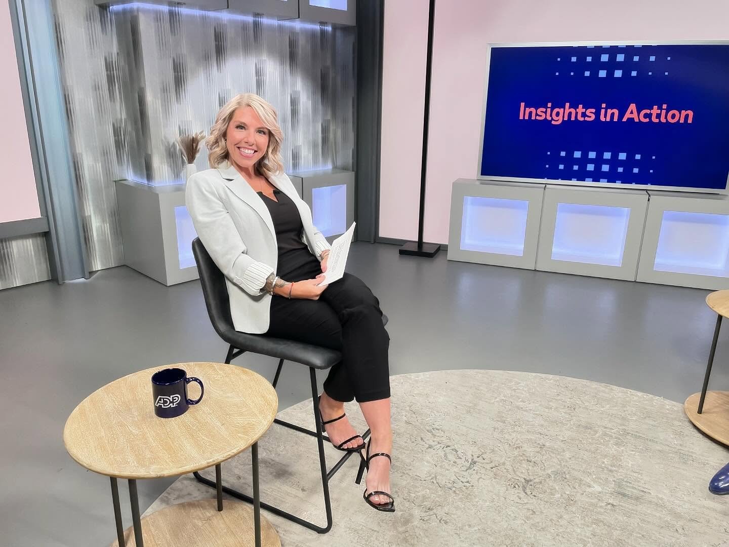 Woman sitting on a chair in a studio with "Insights in Action" displayed on a monitor.