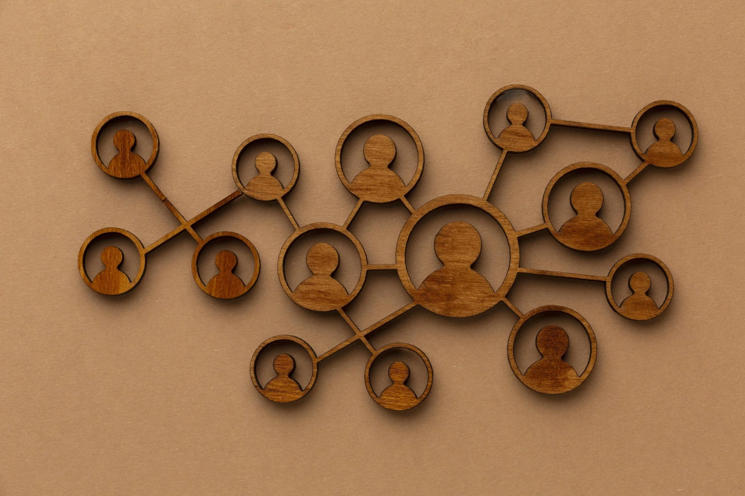 Wooden network diagram with interconnected circles containing person silhouettes on a beige background.