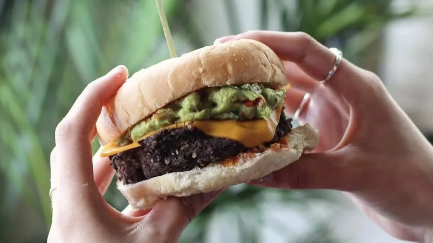 a burger with guacamole in someone's hands